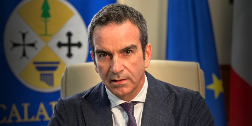 sfondo immagine bandiere unione europea e italiana con lo stemma della regione calabria. in primo piano Roberto Occhiuto Presidente Regione Calabria sui temi del pnrr